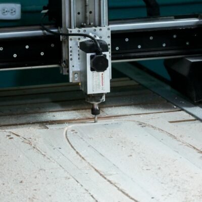 Close-up of a CNC milling machine operating in a workshop setting, cutting patterns into wood.