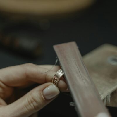 Close-up of a craftsman polishing a gold ring using a tool, showcasing fine jewelry making.