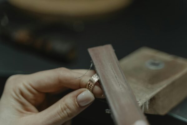 Close-up of a craftsman polishing a gold ring using a tool, showcasing fine jewelry making.