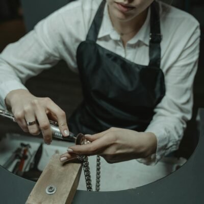 Skilled artisan crafting a necklace in a workshop, showcasing jewelry-making expertise.