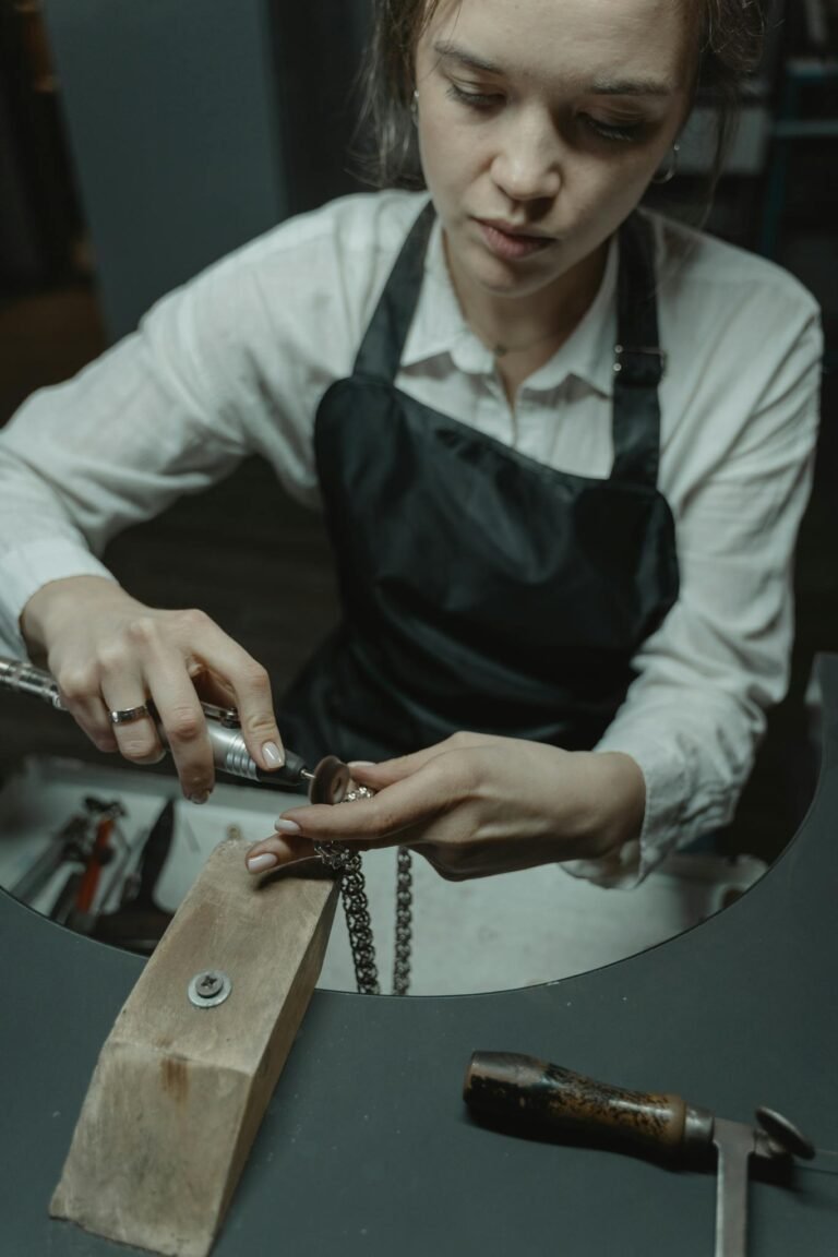 Skilled artisan crafting a necklace in a workshop, showcasing jewelry-making expertise.